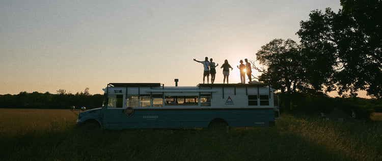 A group standing on a bus at sunset
